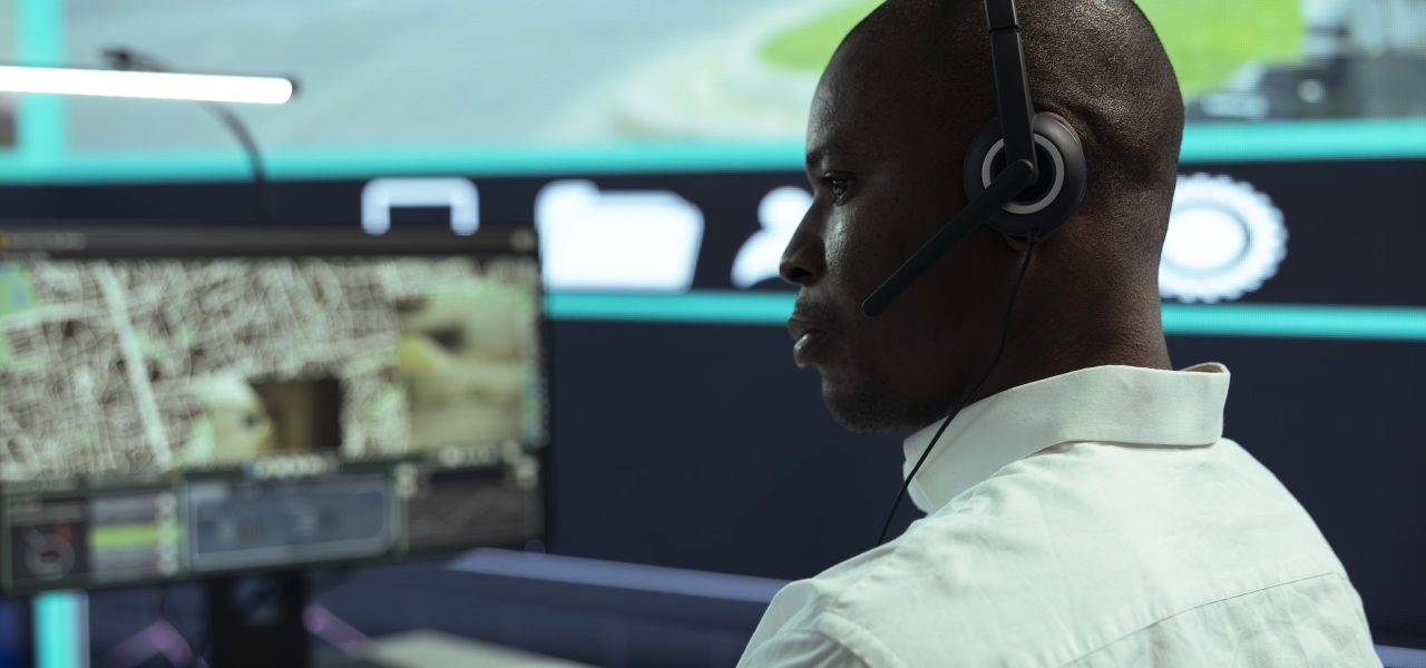 African american guy supervising traffic activity via CCTV system, using surveillance footage and radar in the city. Control center employee tracking cars through security cameras.