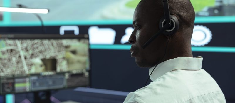 African american guy supervising traffic activity via CCTV system, using surveillance footage and radar in the city. Control center employee tracking cars through security cameras.